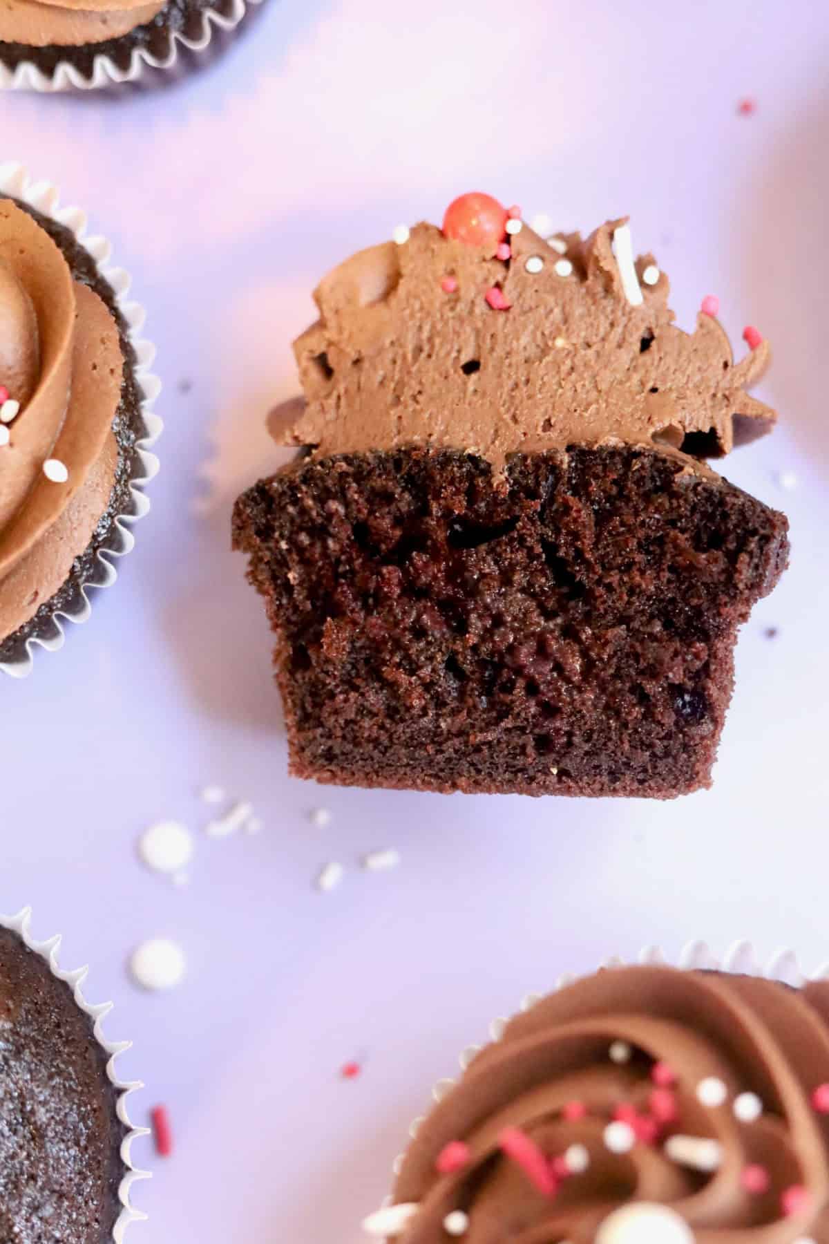 A decadent chocolate cupcake cut in half revealing a velvety, and sponge-like texture.