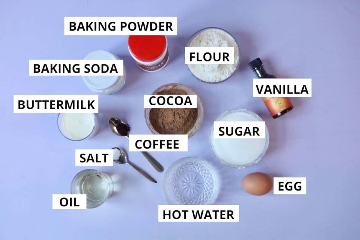 All of the ingredients needed to make decadent chocolate cupcakes displayed on a purple board. Text overlay stating what each ingredient is.