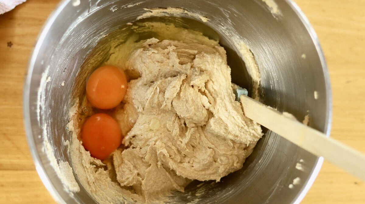 Creamed butter, sugar and oil in a KitchenAid bowl. Two eggs have been added, which are not beaten yet.