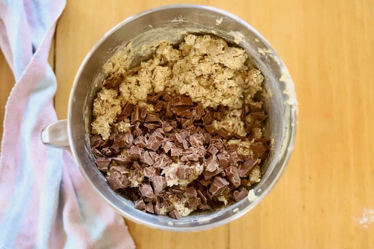 The Whittaker's milk chocolate has been added to the cookie dough mixture in a bowl.