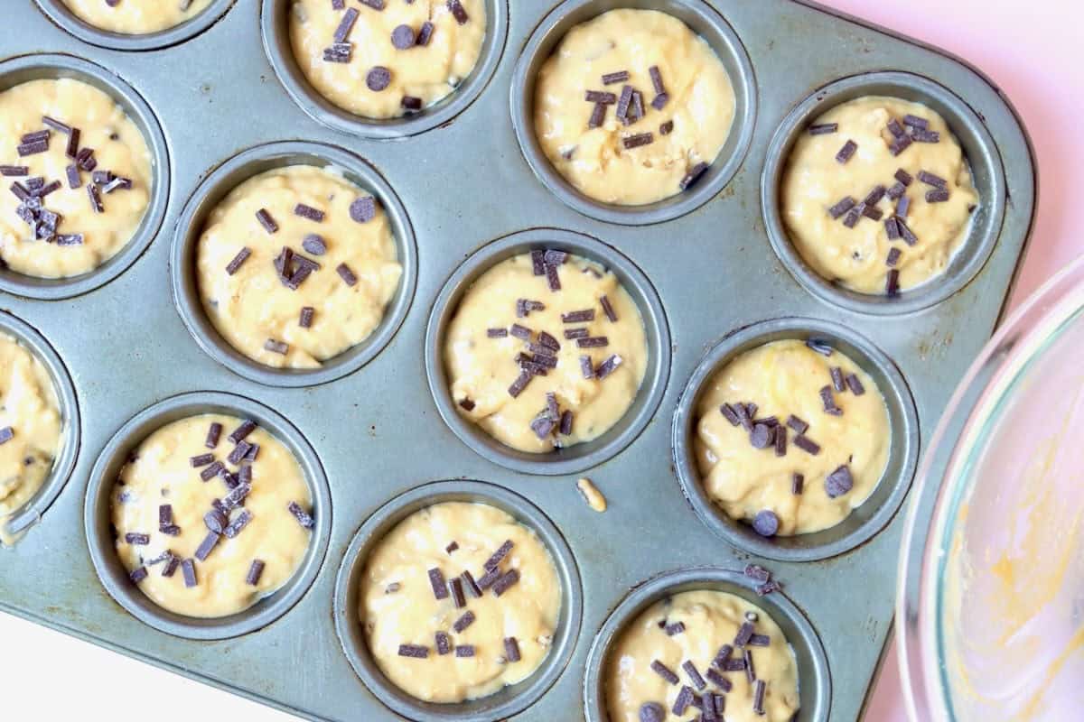 Muffin mixture in a greased muffin tin before baking.