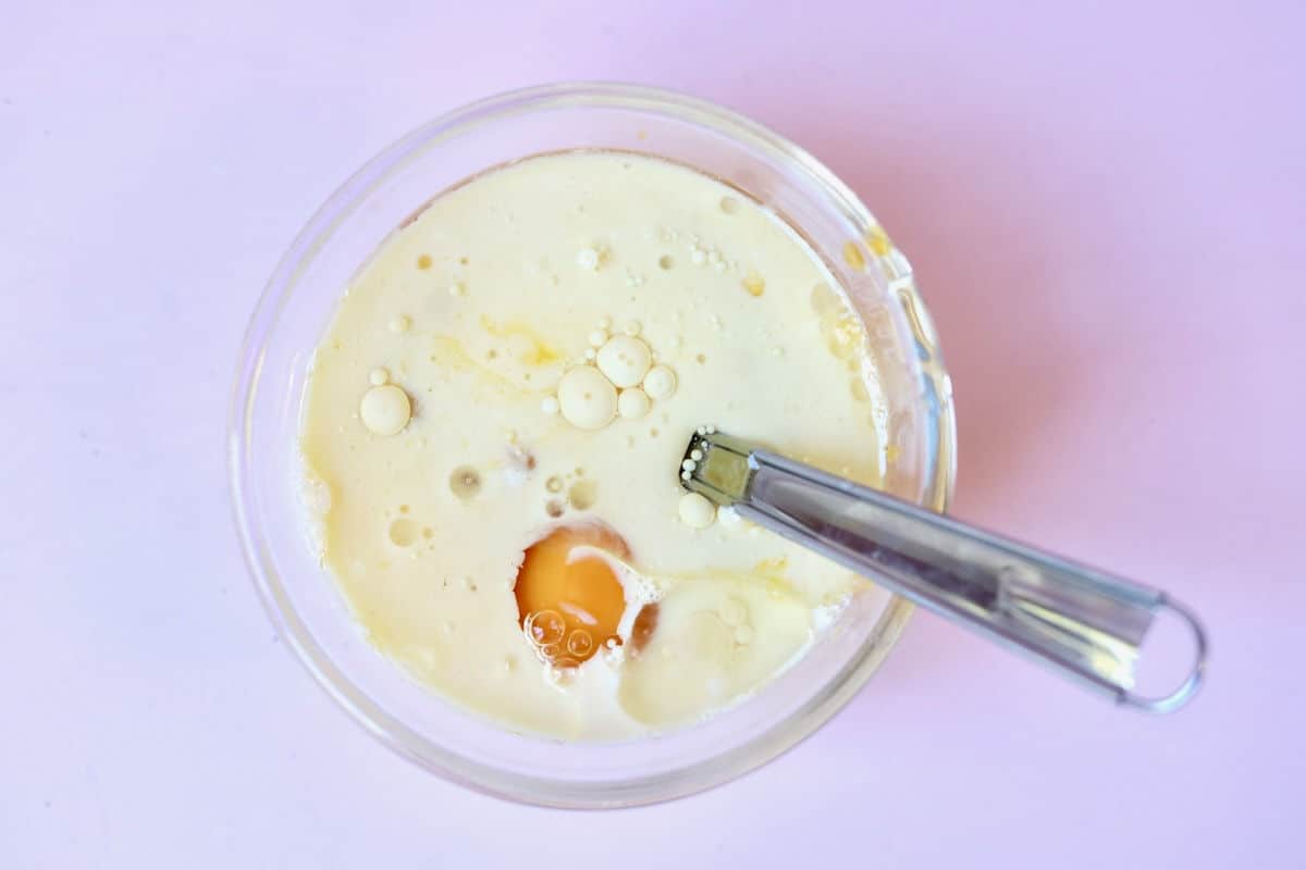 Wet ingredients (i.e. egg, buttermilk and vanilla) in a glass bowl in preparation for using the muffin method.
