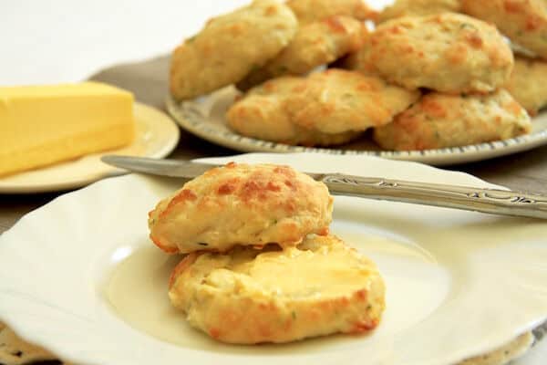 A zucchini and feta scone which has been cut in half and filled with butter.