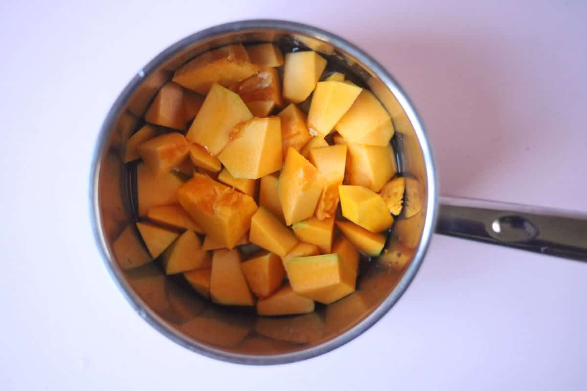 Pieces of chopped up pumpkin in a pot with some water.